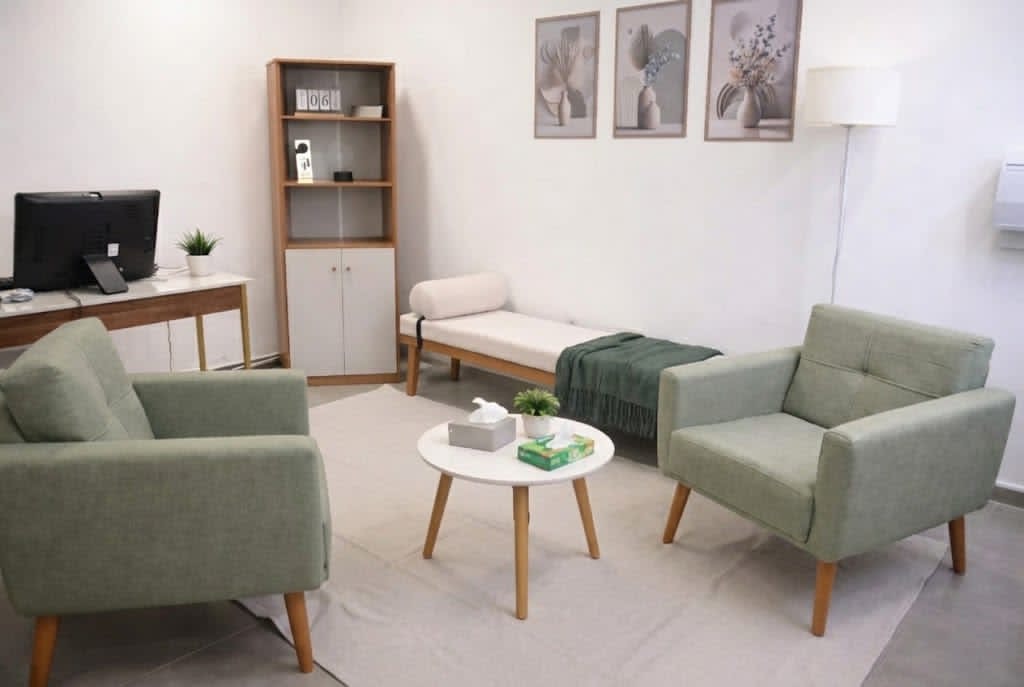 Sala real de atendimento em Campinas, com duas poltronas verdes, mesa e divã